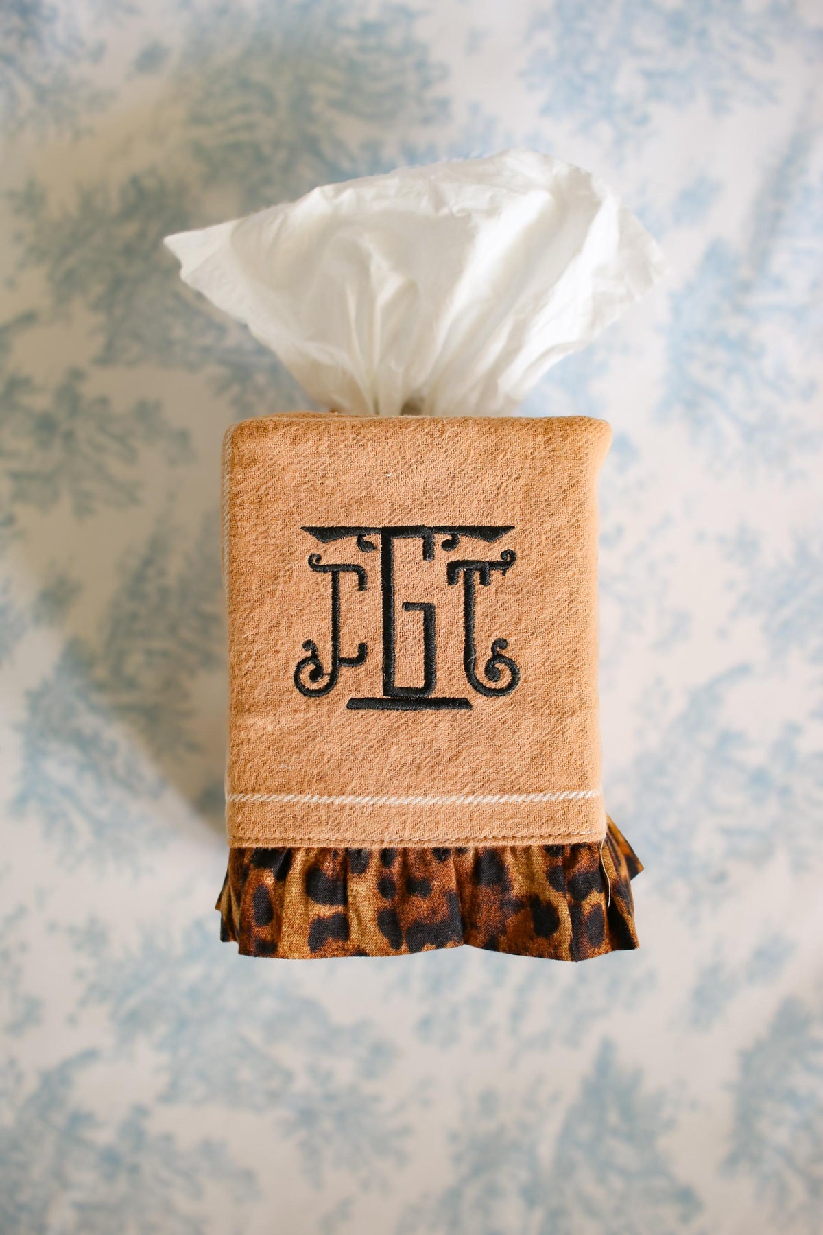 camel stripe tissue box cover with cheetah ruffle detailing and black custom embroidered monogram on blue toile background