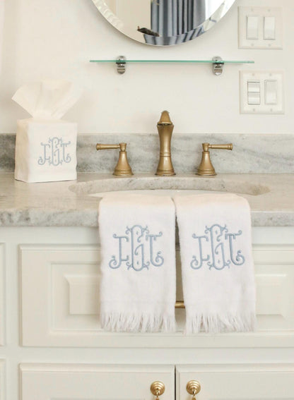 Monogrammed bathroom set arranged for gifting, featuring two fingertip towels and a tissue box cover with custom embroidered initials.
