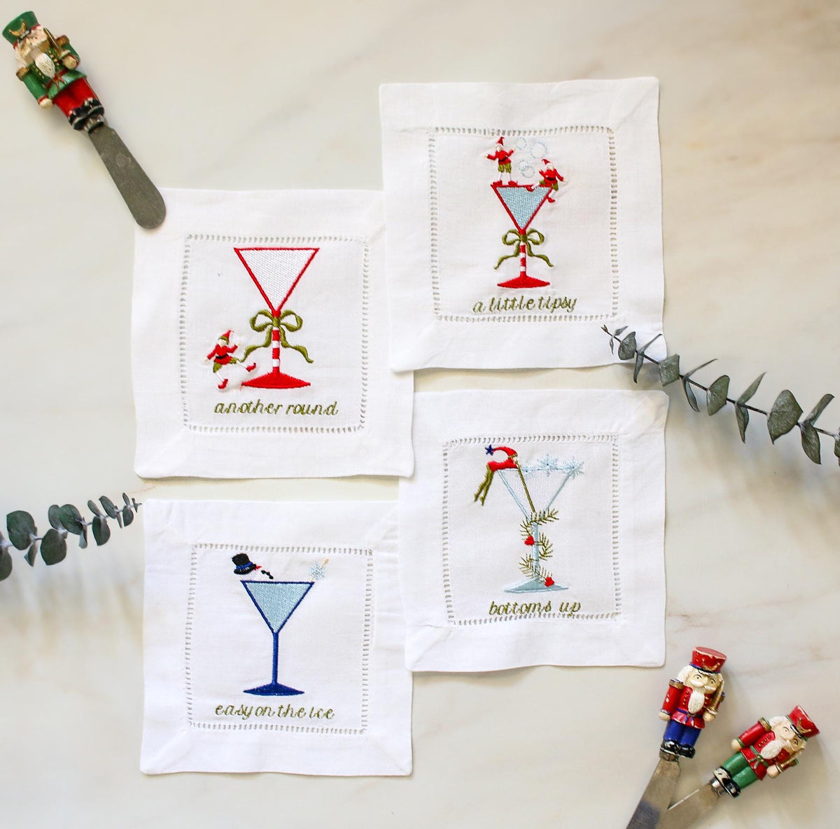 Set of 4 embroidered Christmas cocktail napkins – holiday martini glass designs with festive sayings, linen hemstitch coasters.