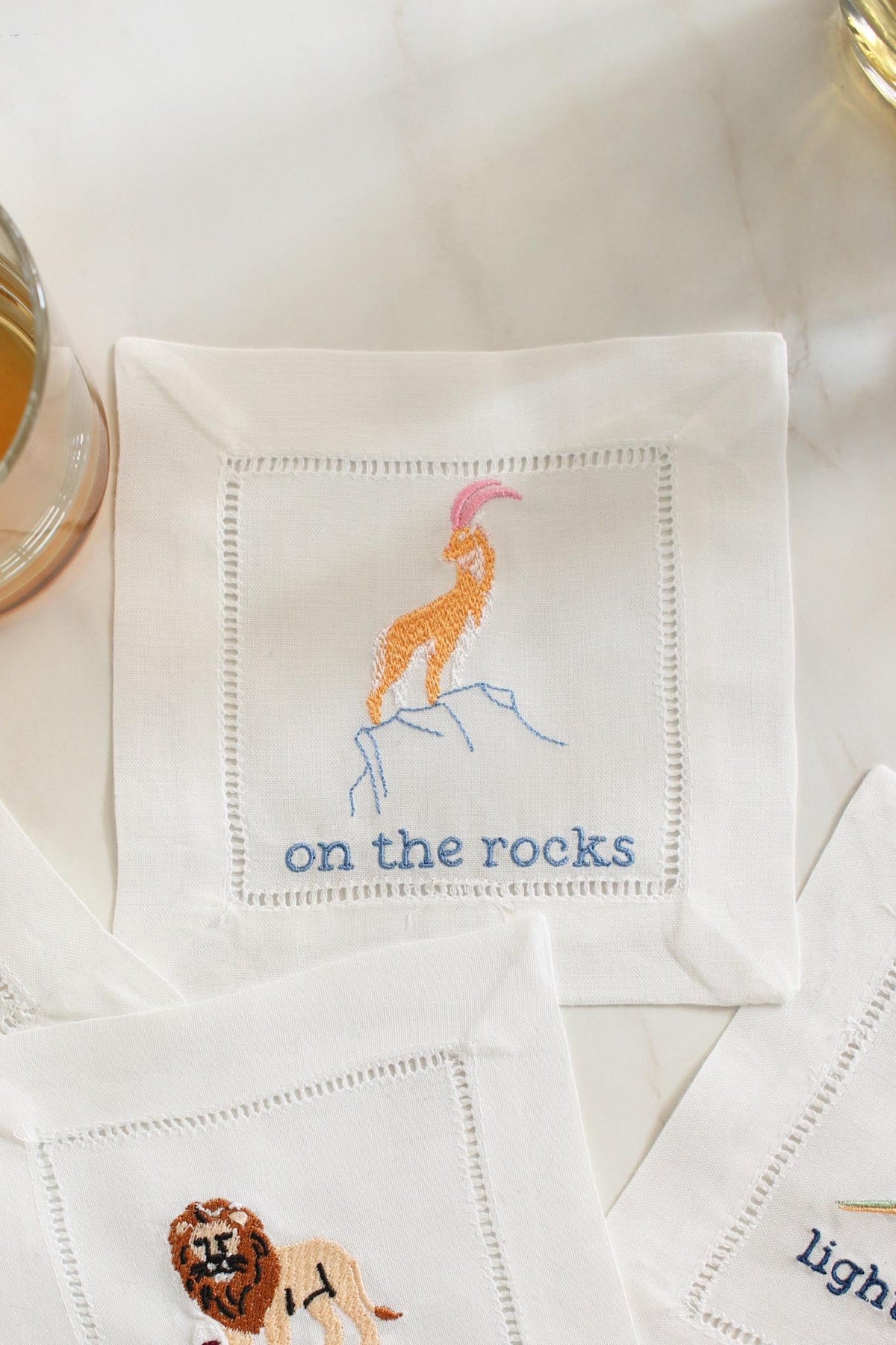 Goat embroidered linen cocktail napkin with the phrase On the Rocks